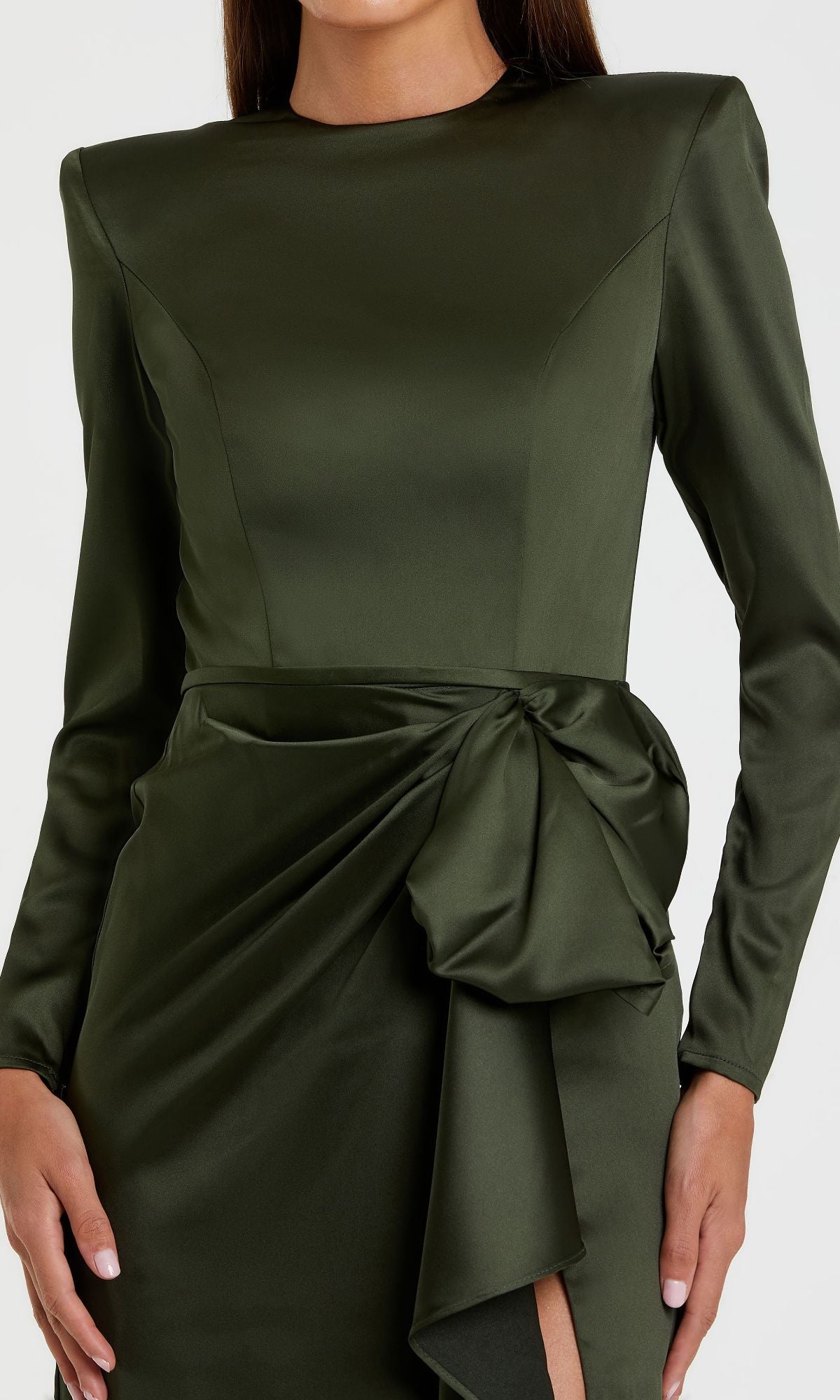 A woman wears the Mac Duggal 26676 Bold-Shoulder Long Formal Dress in dark green satin, featuring bra-friendly long sleeves, padded shoulders, and a draped bow detail at the waist.